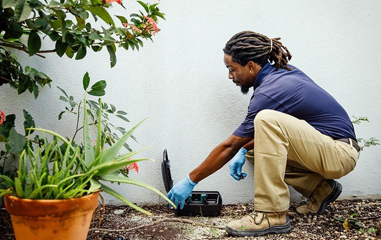 Technician treating for rodents outside home