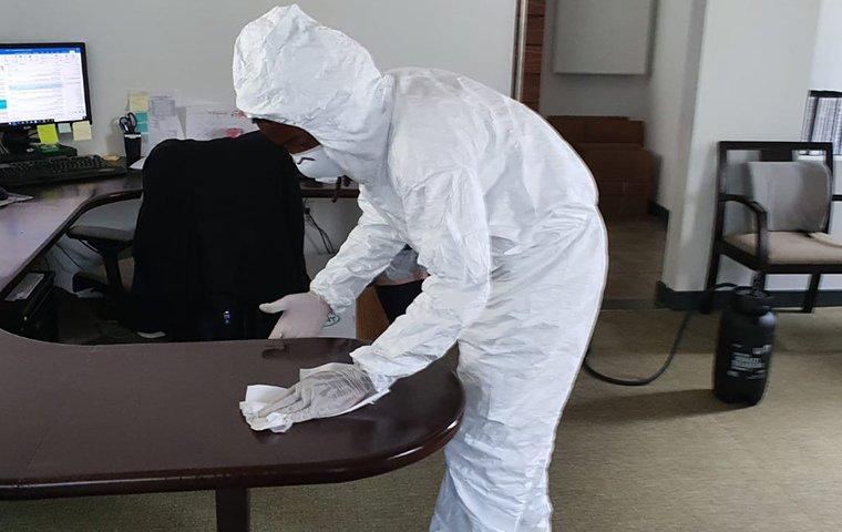 Technician sanitizing office desk